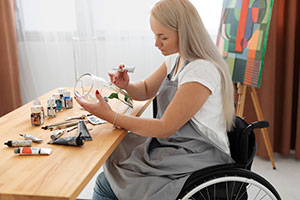 Woman in Wheelchair Painting a glass vase.