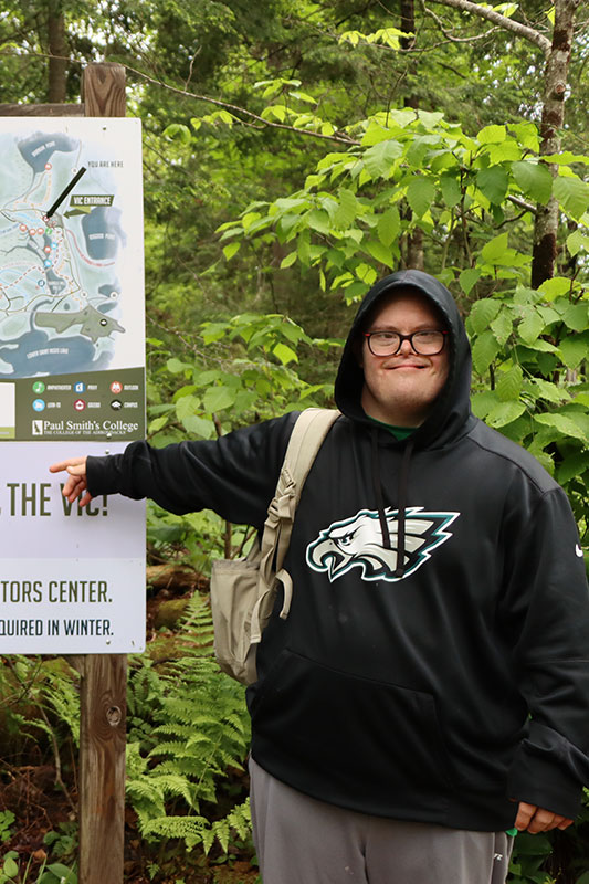 Man with disability smiling at VIC sign Adirondack Nature Festival for People with Disabilities