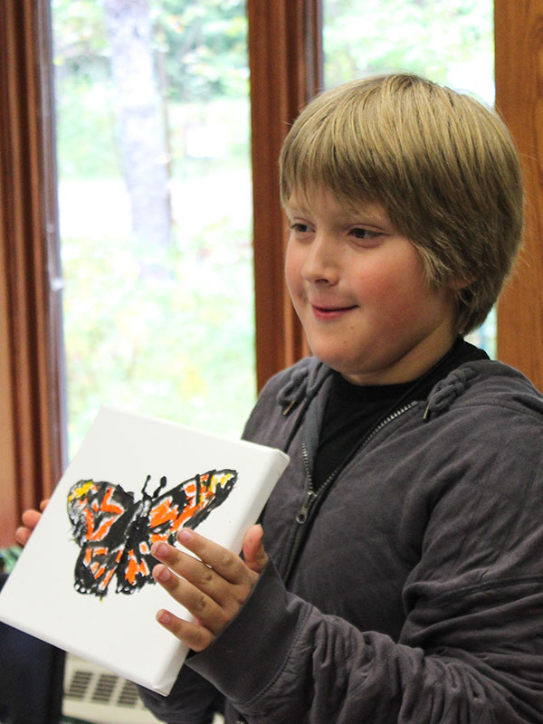 Young Boy Holding Painting of Monarch Butterfly